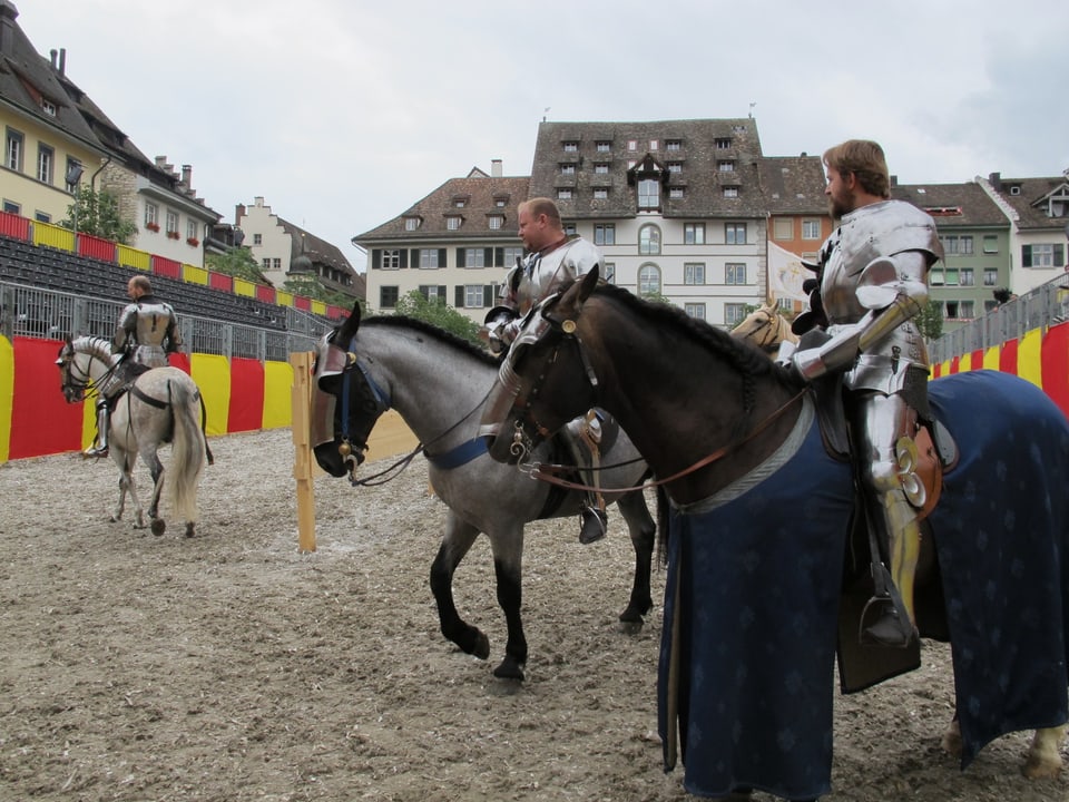 Männer zu Pferde und in Rüstungen besichtigen den Turnierplatz Herrenacker.