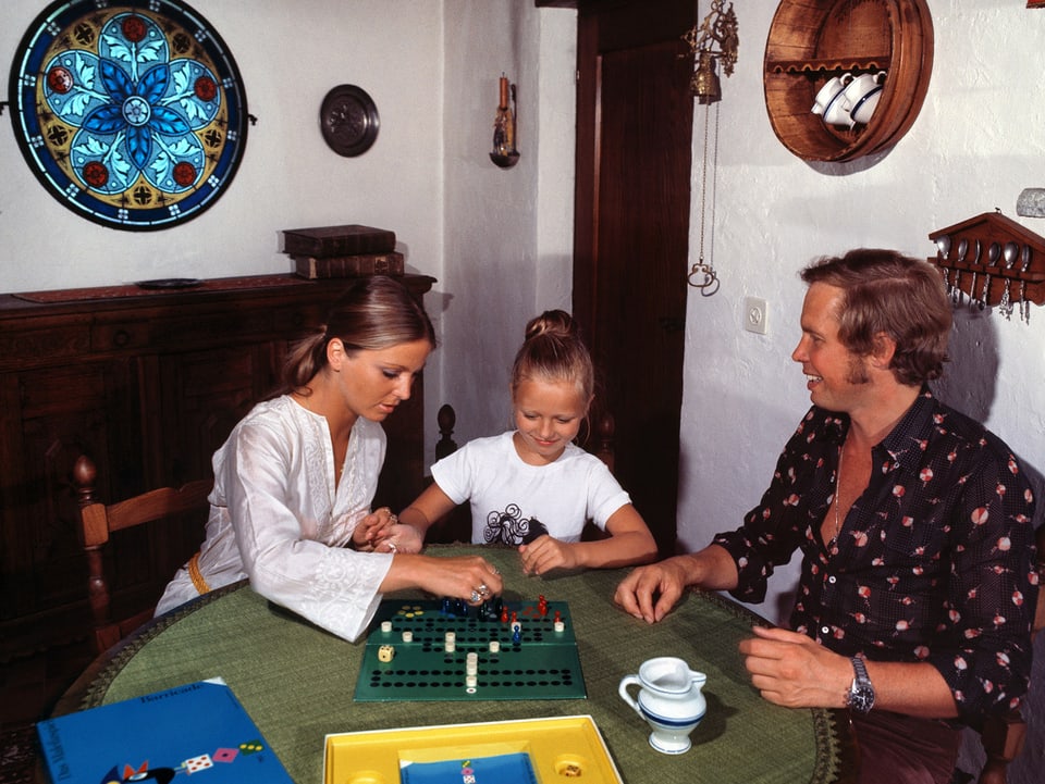 Die junge Familie spielt Halma im rustikal eingerichteten Wohnzimmer.