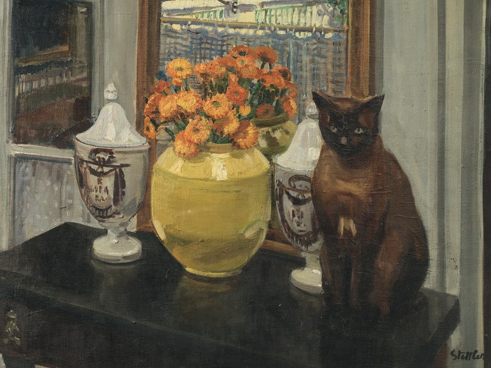 Auf einem Tisch vor dem Fenster befindet sich eine Vase mit Blumen, weitere Keramikgefässe, daneben sitzt eine Katze.