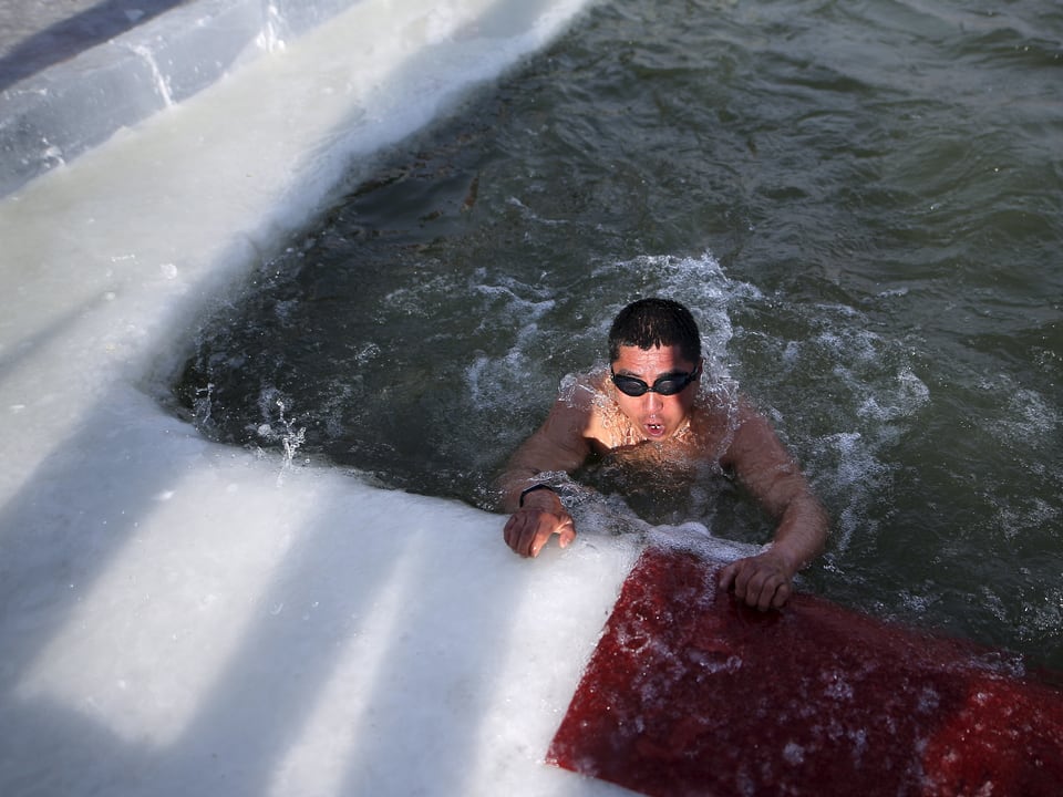 Ein Mann schaut aus einem Schwimmbecken aus Eis heraus
