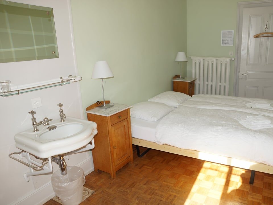 Einblick in ein Hotelzimmer mit Doppelbett und Lavabo.
