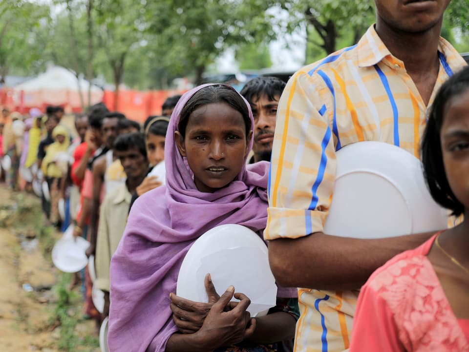 Geflüchtete Rohingya warten in einer Schlange auf etwas zu Essen.