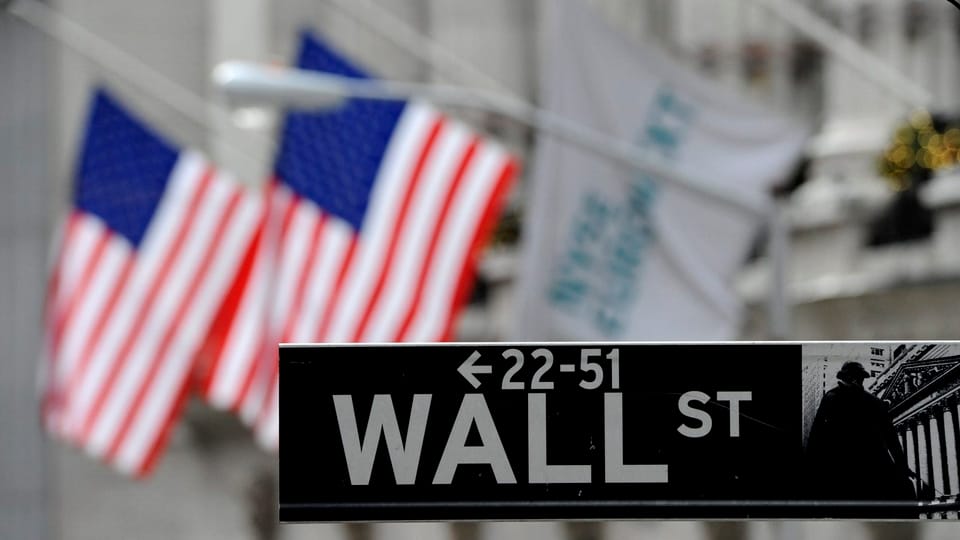 Wall Street-Strassenschild vor zwei amerikanischen Flaggen.