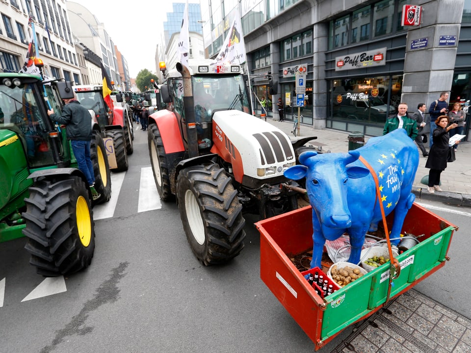 Traktore versperren die Strasse. Ein Traktor hat eine grosse Milch-Skulptur geladen.