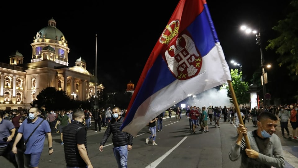 Demonstranten mit Serbischer Fahne vor dem Parlamentsgebäude in Belgrad.