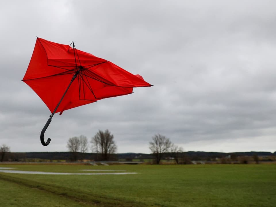 Ein kaputter, roter Schirm in der Luft.