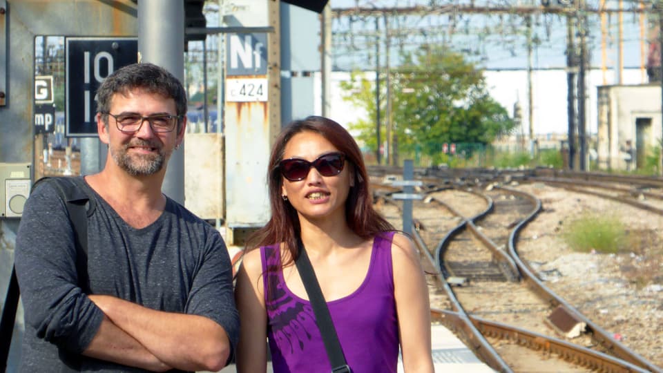 Ein Mann und eine Frau stehen am Bahnhof