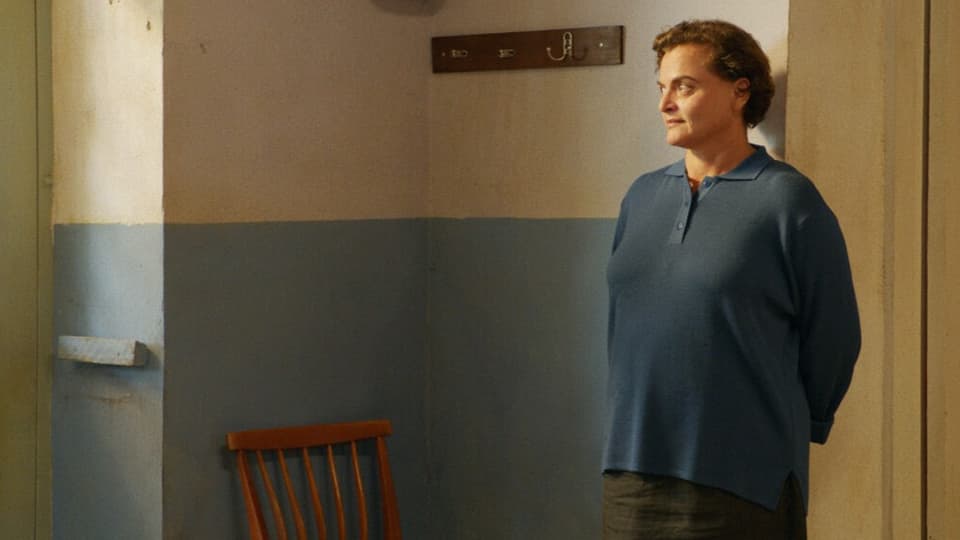 Eine Frau mittleren Alters steht in einem Türrahmen.