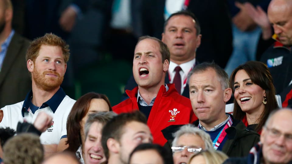 Prinz Harry, Prinz William und Herzogin Kate schauen sich ein Rugby-Spiel an.