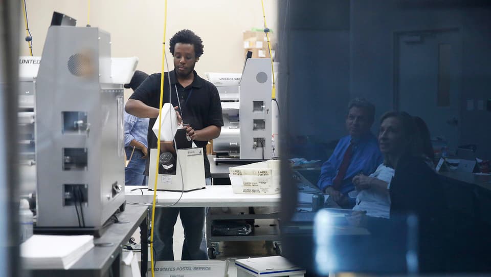 Mann sortiert Stimmzettel in Maschine ein