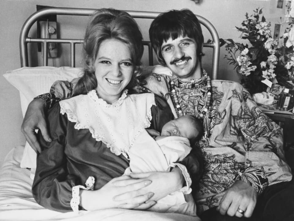 Bild von Ringo und Maureen. Sie liegen im Bett und sie hält Sohn Jason im Arm. Beide lächeln.