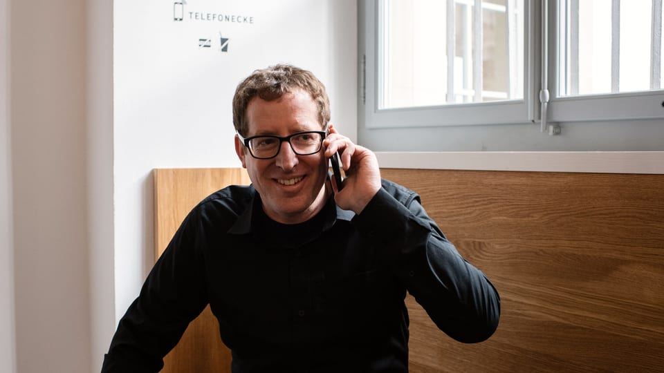 Ein Mann sitzt auf einer Bank und telefoniert mit seinem Smartphone.
