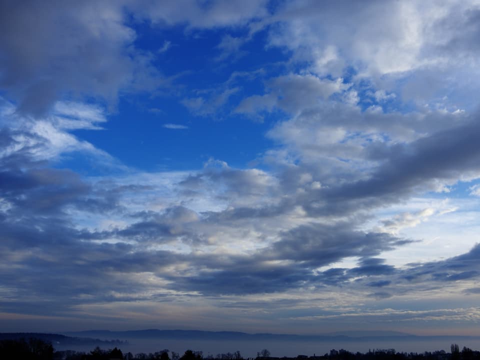 Blauer Himmel mit einigen Wolken, unten der Bodensee ganz knapp ersichtlich