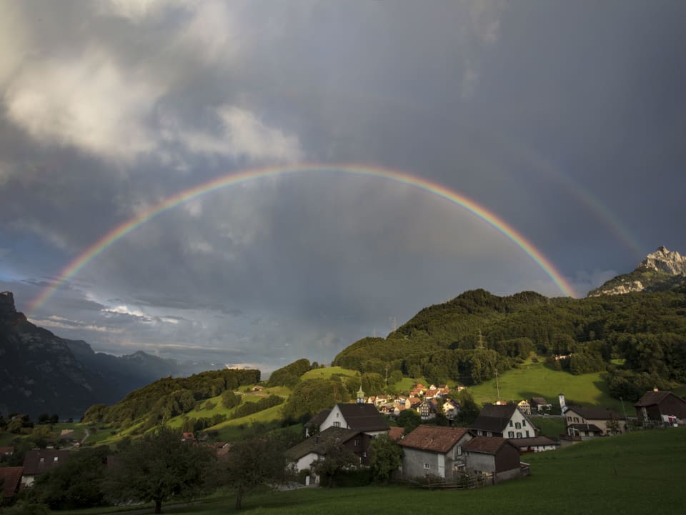 Regenbogen überspannt Tal.