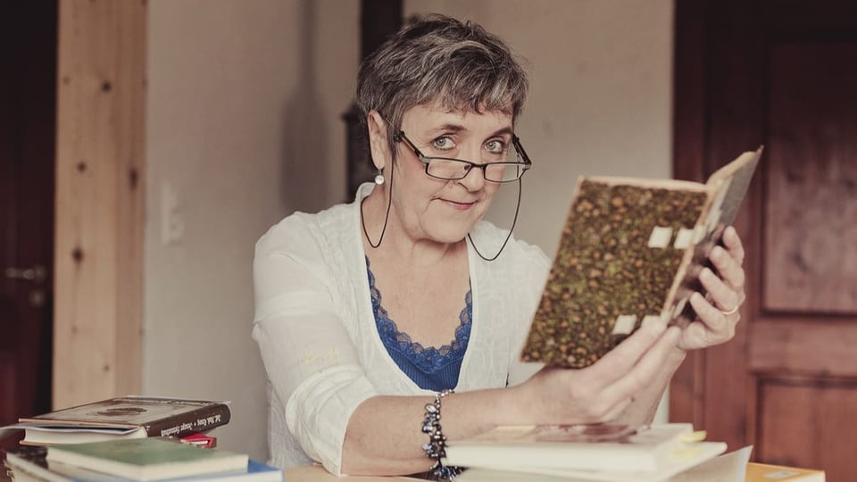 Eine Frau mit Brille mit einem aufgeschlagenen Buch.