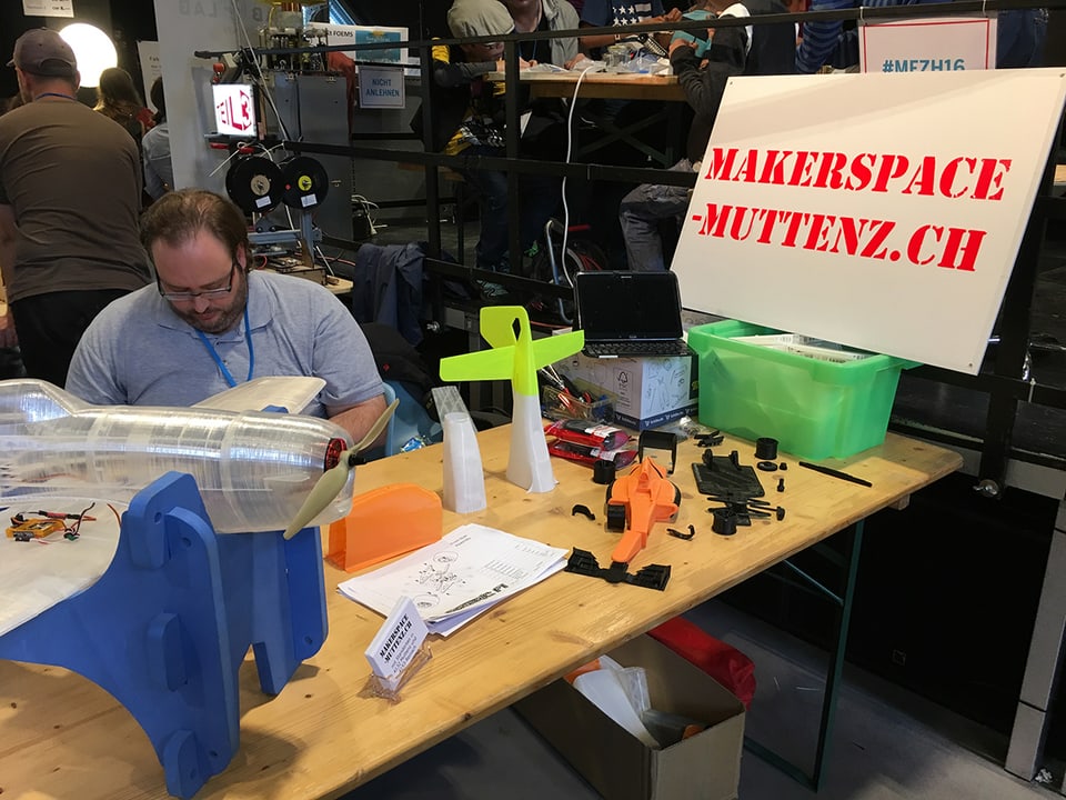 Ein Mann vom Makerspace Muttenz sitzt an einem Tisch mit einem  3D-gedruckten Flugzeug.