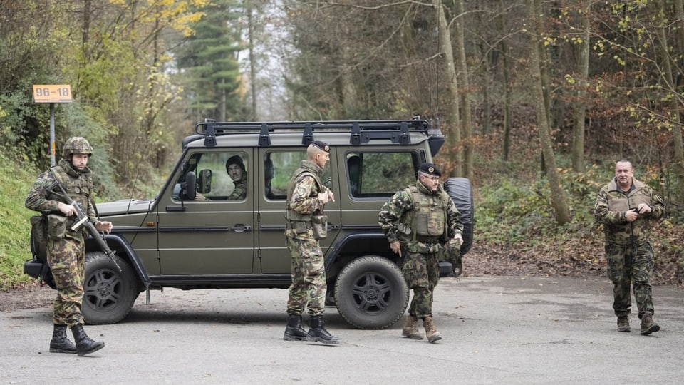 Soldaten der Schweizer Armee stehen um ein Auto.