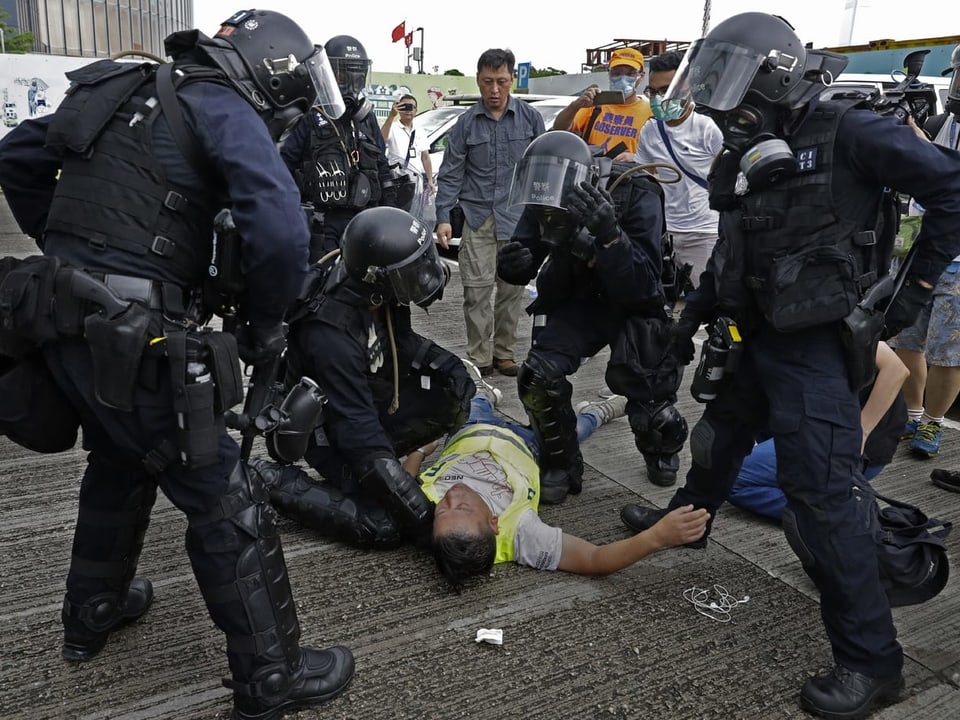 Verletzter Kameramann am Boden, umringt von Polizisten
