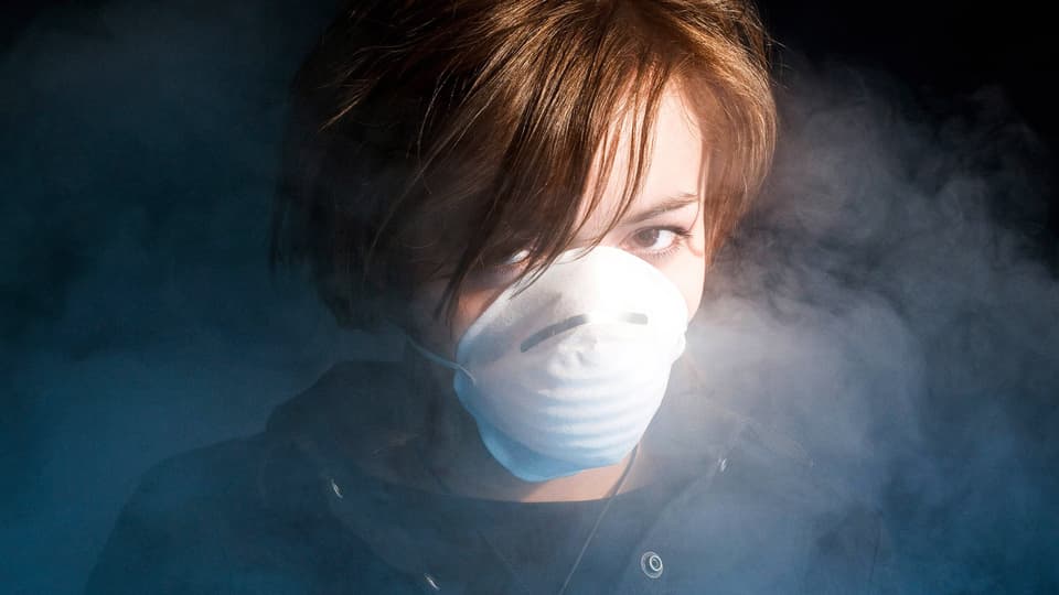 Frau mit medizinischer Schutzmaske in Rauchwschwaden