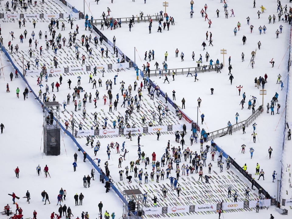 Die Skier der Teilnehmenden liegen geordnet auf dem Boden beim Engadin Skimarathon.