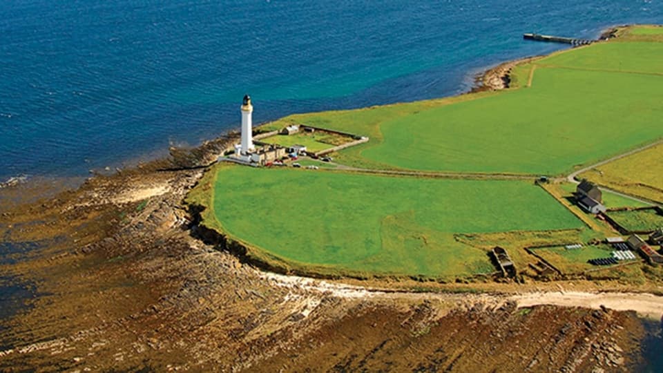 Vogelperspektive auf eine saftig grüne Insel mit einem weissen Leuchtturm