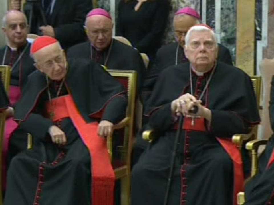 Ältere Bischöfe sitzen auf ihren Stühlen.