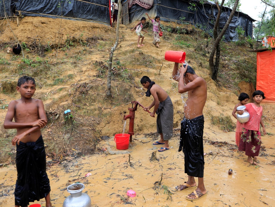 Kinder waschen sich im Flüchtlingslager im Freien.