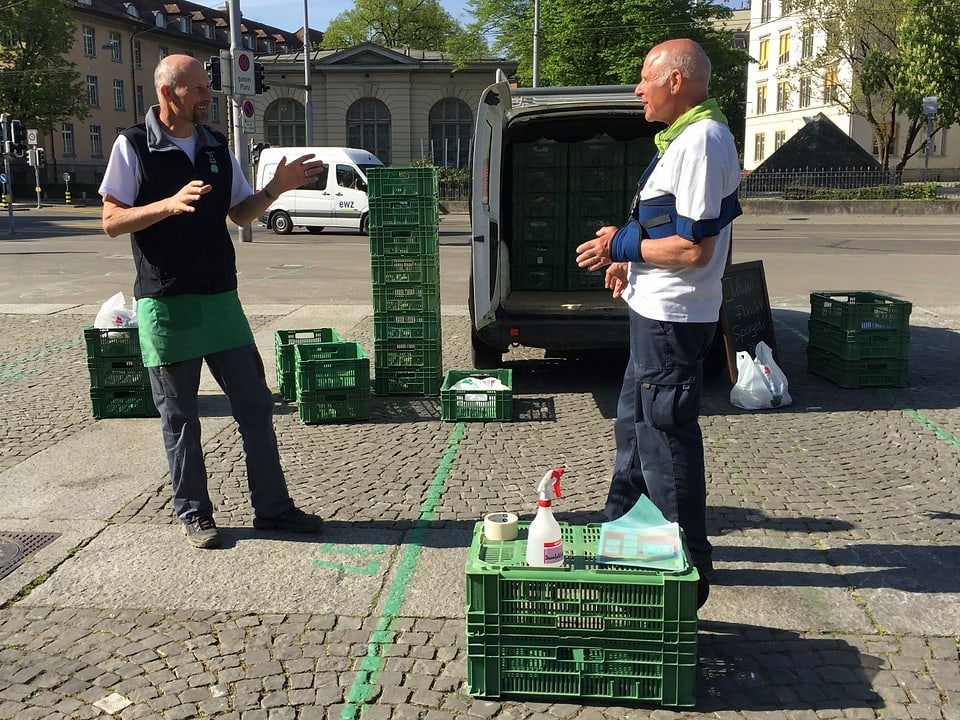 Zwei Mitglieder des Familienbetriebs Haab Walser stehen vor ihren ausgeladenen Gemüsekisten auf einem Platz in der Stadt Zürich.
