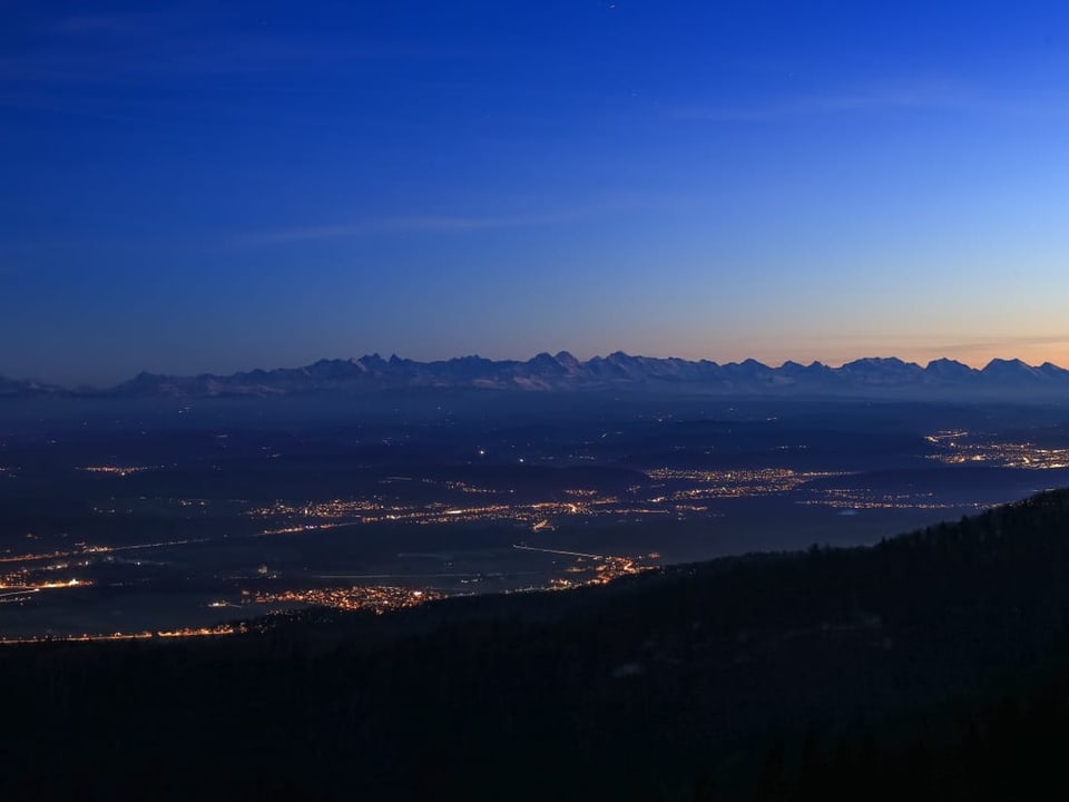 Blick ins Mittelland mit den Bergen im Hintergrund während der Nacht