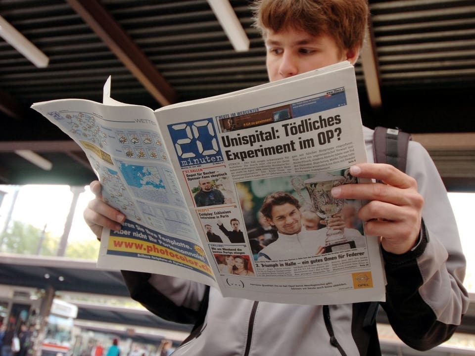 Junger Mann liest die Gratiszeitung «20 Minuten».