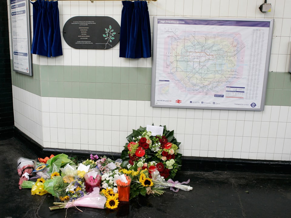 Blumen vor einer Karte und einer Gedenktafel
