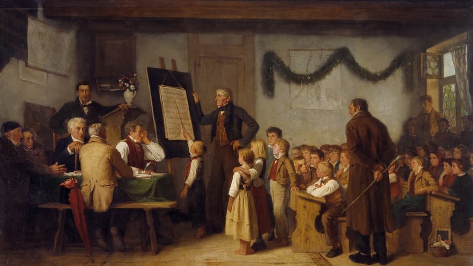 Ein Gemälde einer Unterrichtsstunde mit vollen Schulbänken zu rechten und einer Tafel und Lehrern zur linken.
