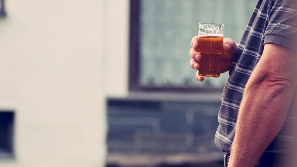 Ein nicht näher erkennbarer Mann hält ein Bierglas in der Hand.