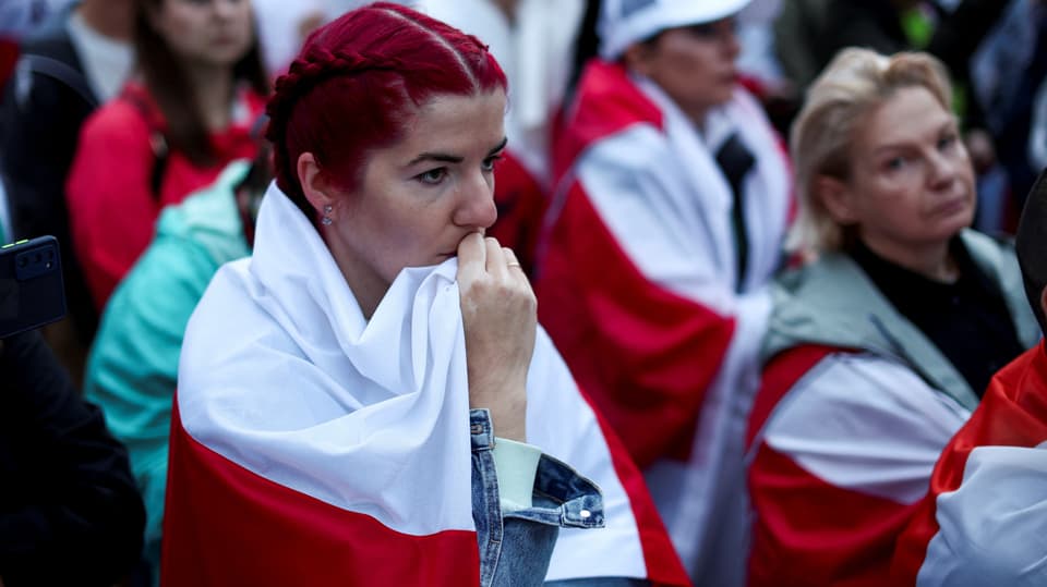 Frauen in weiss-roten Flaggen gehüllt.
