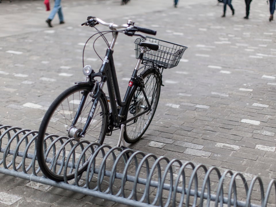 Ein Velo in einem Ständer auf Kopfsteinpflaster.