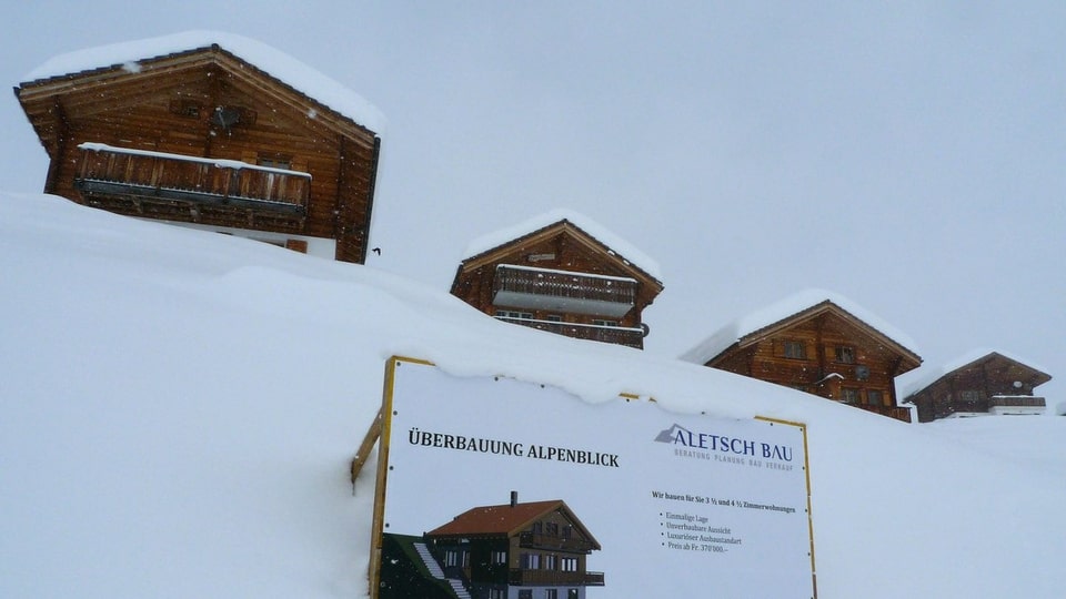 Vier Chalets im Schnee in Belalp, davor ein Schild «Überbauung Alpenblick» der Firma Aletsch Bau.