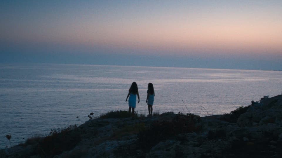 Zwei Mädchen stehen vor dem Meer.