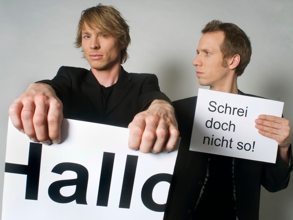 Jonas Anderhub und Christof Wolfisberg halten ihre Zettel hoch.