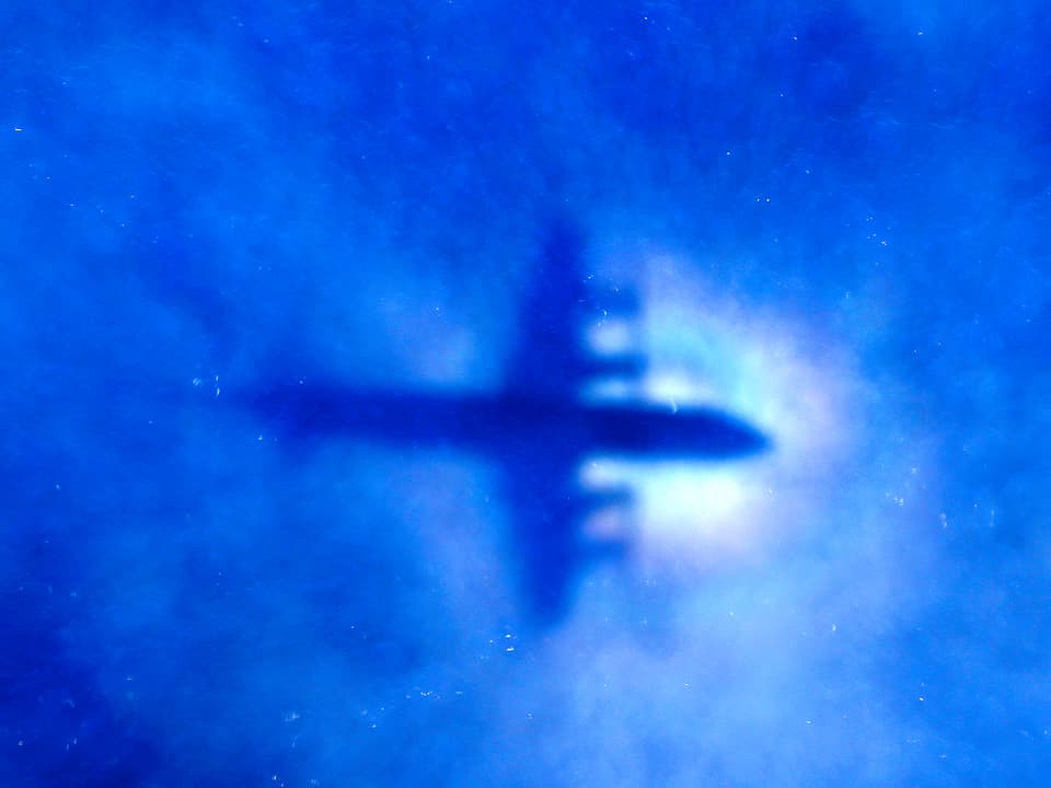 Schatten eines Suchflugzeugs hinter dünnen, blauen Wolken im südindischen Ozean.