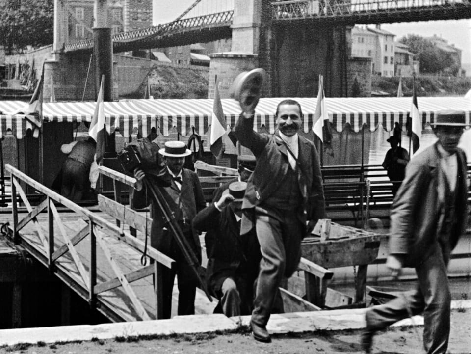 Schwarz-Weiss-Bild: Leute steigen über eine Brücke auf das Festland.