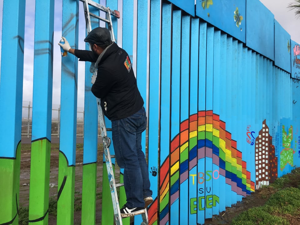 Enrique Chiu besprüht Mauer der Brüderlichkeit mit Farbe.