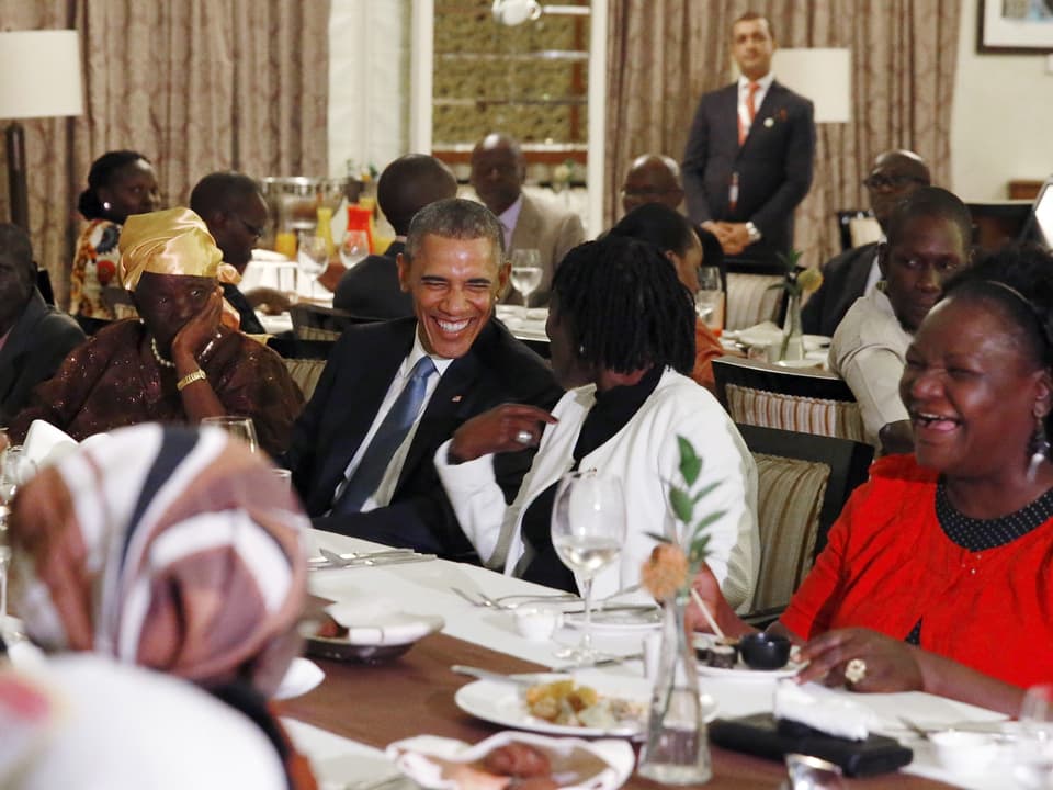 Barack Obama sitzt mit Familienangehörigen am Tisch eines Restaurants. 