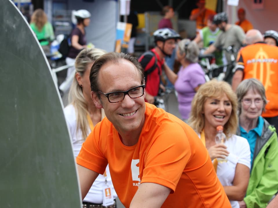 Porträt Christian Zeugin im orangen T-Shirt.
