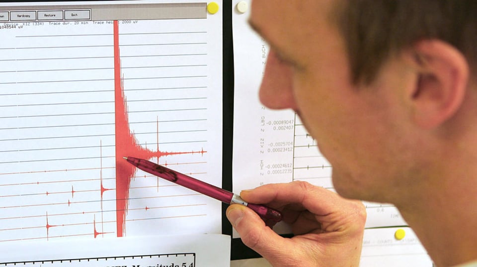 Ein Mann zeigt auf eine rote Erdbeben-Kurve