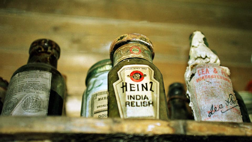 Uralte Saucenflasche von Heinz, die neben anderen Flaschen auf einem Regal steht.