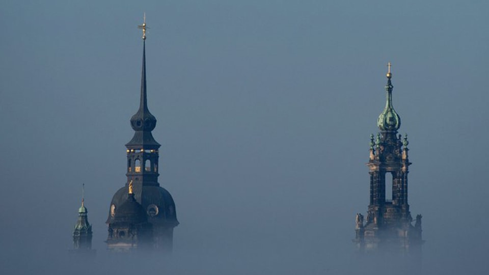 Zwei Kirchtürme, die aus dem Nebel ragen. 