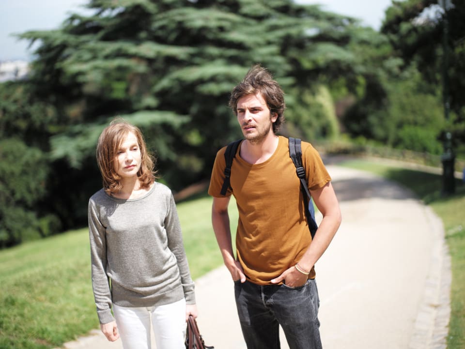 Eine Frau und ein jüngerer Mann laufen durch grüne Landschaft. 