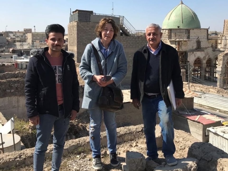 Susanne Brunner, Leiterin Auslandredaktion, steht mit zwei Interviewpartnern auf einem Haus in Mosul im Norden des Irak.