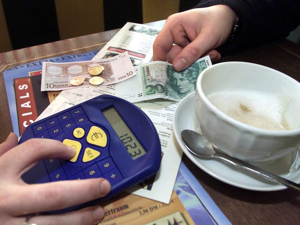 Bezahlvorgang in einem Cafe. Ein Taschenrechner liegt auf dem Tisch.