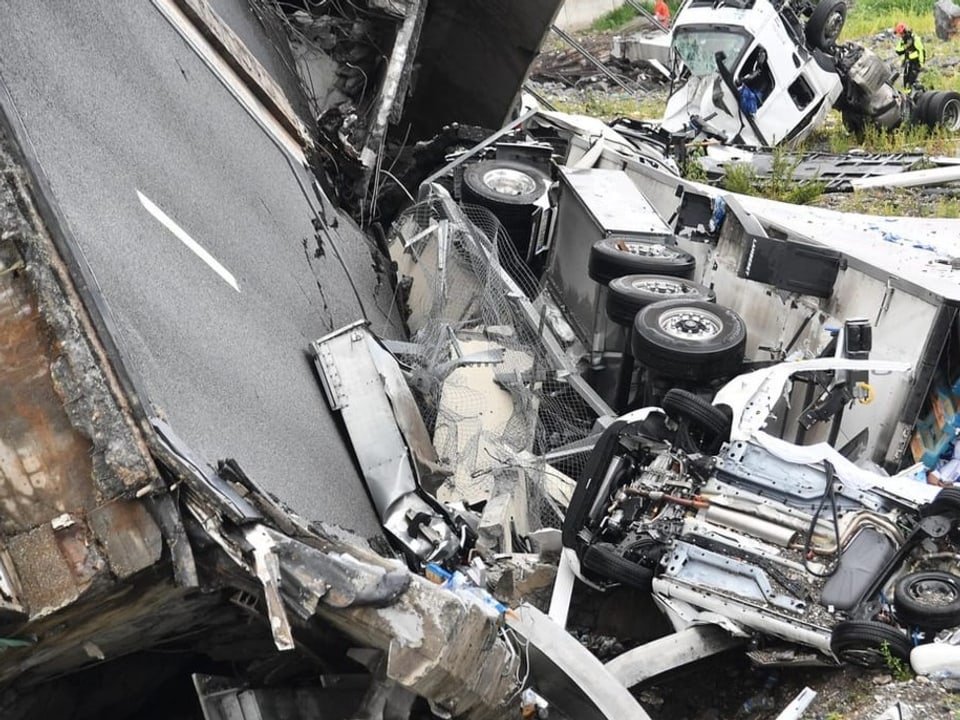 Abgebrochener Asphalt, zerstörte LKWs und Auto – die puure Zerstörungskraft einer heruntergestürzten Brücke.